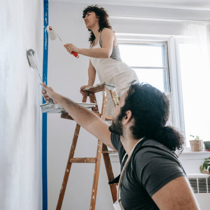 PaintA couple painting an interior wall white together.
